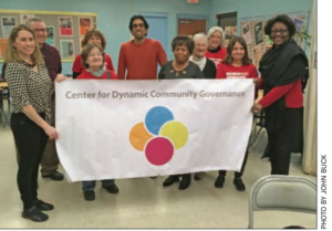 About 10 people in a room holding a banner that says Center for Dynamic Community Governance 